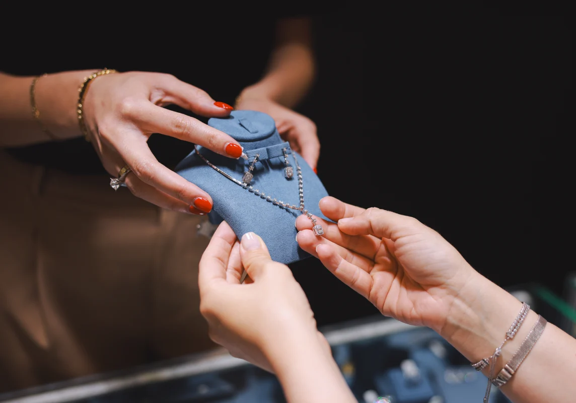 Hands examining a necklace display